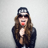 girl in  black cap and earphones in hands.On  gray background holding in hand an icicle