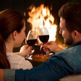 Couple with glass of wine at fireplace